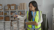 © Krakenimages.com - Woman organizing food supplies in a charity center, wearing a reflective vest, focused on volunteering tasks within an indoor setting, highlighting community service involvement.