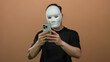 © Krakenimages.com - Caucasian man with a beard wearing a mask takes a selfie against an isolated brown wall background.