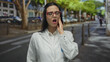 © Krakenimages.com - Hispanic woman wearing lab coat holding cheek outdoors on busy urban street appearing to have a toothache.