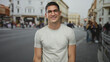 © Krakenimages.com - Man with glasses smiling and looking up, bare forearms visible, wearing a white t shirt on a busy street with historic buildings; confidence.
