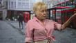 © Krakenimages.com - Woman points finger on busy london street by red bus and phone box, striped shirt visible, hand raised and gaze directed forward; assertive concern.