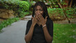 © Krakenimages.com - African american woman covering mouth with hands on forest path wearing black top and bracelet; surprise wonder.