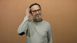 © Krakenimages.com - Man posing thoughtfully against brown background in casual outfit and glasses appearing inquisitive and engaged.