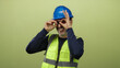© Krakenimages.com - Man wearing blue helmet and yellow vest gestures playfully against green background, showcasing expression and personality