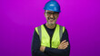 © Krakenimages.com - Confident man wearing hardhat and vest smiling with crossed arms against vibrant pink background showcasing construction industry and safety gear.