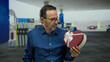 © Krakenimages.com - Mature hispanic man in blue shirt holding heart-shaped gift box at petrol station with contemplative expression.