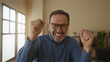© Krakenimages.com - Mature hispanic man in office expressing various emotions wearing glasses and a blue shirt in a bright interior space with books and plants in the background