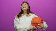 © Krakenimages.com - Woman smiling holding basketball against vibrant pink wall emphasizing contrast and youthful happiness in a sports context