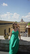 © Krakenimages.com - Woman sitting on a stone wall on a rome street in a green dress and sunglasses, looking up toward a domed building; serenity travel wanderlust.