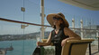© Krakenimages.com - Woman in straw sunhat holding a champagne glass on a cruise ship terrace with glass railing and sea view; relaxation leisure.