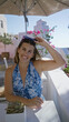 © Krakenimages.com - Woman laughing with hands on table at terrace restaurant in santorini town; summer joy relaxation bliss.