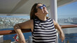 © Krakenimages.com - Young woman leaning with bare arms on railing, smiling and wearing sunglasses on a building terrace; relaxation summer travel.