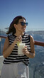 © Krakenimages.com - Woman sipping a creamy pineapple cocktail through a straw while holding the glass by the rail on a cruise deck; relaxation holiday getaway.