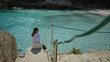 © Krakenimages.com - Woman relaxing by turquoise sea at cala llombards beach in mallorca, overlooking the stunning mediterranean scenery, enjoying serene vacation moments under bright sunlight.