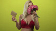 © Krakenimages.com - Blonde woman holds pink bouquet and brown envelope with cleavage visible in green studio scene; happiness.