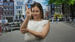 © Krakenimages.com - Woman making finger to lips and a pointing gesture on street in front of canal houses with uncovered fingers and forearm visible; silence secrecy.