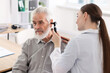 © New Africa - Hearing test. Doctor examining patient’s ear with otoscope in clinic