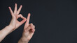 © Михаил Решетников - Woman showing the word goal in Russian sign language on black background.