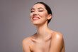 © Beauty Hero - Gorgeous young woman with radiant skin and confident smile posing gracefully against a soft gray background