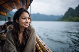 Smiling young woman enjoying a serene boat ride on a misty mountain lake — peaceful travel portrait capturing adventure, relaxation and natural beauty
