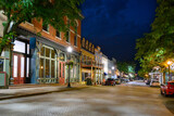 Early American buildings with shops and boutiques line the brick paved Main Street in the historic small town of St. Charles Missouri at night.