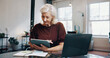 © MagicDavid25/peopleimages.com - Reading, research and tablet with woman at desk in small business startup for feedback or review. App, laptop and notebook with mature employee in office for online planning, report or strategy