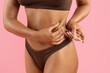 © Anastasiya - Closeup of young black woman injecting syringe in belly fat area on pink background. Symbolic weightloss treatment scene highlighting body sculpting, fitness progress and modern beauty care