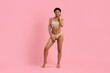 © Anastasiya - Full length portrait of smiling young black woman in beige underwear posing confidently on pink studio background. Fit body and natural expression highlight beauty and modern lifestyle themes