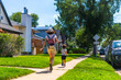 © unai - Mother and son running on sidewalk in suburban neighborhood of drumheller, canada