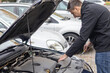 © Галя Дорожинська - Man is removing the engine cover of a car using a screwdriver in a parking area