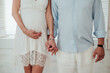 © Bohdan - Pregnant couple holding hands in white lace dress