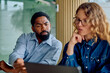 © we.bond.creations - Two diverse professionals concentrating, discussing, and collaborating on a laptop project during an office meeting