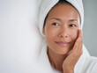 © sam richter - Smiling woman wrapped in white towel enjoys relaxing spa skincare treatment routine.