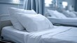 © Asmaa_Asmadi - Clean empty hospital bed with white pillows and blue curtains