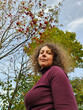 © Pavel Losevsky - Woman with curly hair is standing in front of a rowan tree. She is wearing a purple shirt