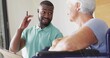 © vectorfusionart - Talking caregiver mint-polo gesturing with pen and tablet in clinic by wheelchair, woman blue-top