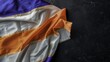 © wan - Colorful satin fabric with purple, white, and orange stripes draped on a dark surface