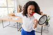 © Pixel-Shot - Angry African-American businesswoman shouting into megaphone in office
