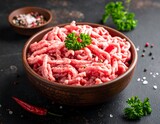 Close-up of raw minced meat in a rustic bowl, surrounded by spices, herbs, and dark background