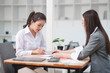 © Thitisak - Asian businesswoman sitting at work using laptop talking and consulting in office