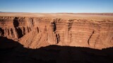 Vast desert canyon with stunning red rock formations under a clear blue sky.