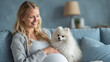© Katerina Bond - Smiling pregnant woman sitting on a couch with a fluffy white Pomeranian, highlighting motherhood, comfort and the bond between pets and expectant mothers.