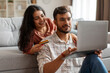 © Home-stock - Easy payments. Happy Indian couple with laptop and credit card making online shopping, enjoying internet purchases, resting in living room at home
