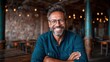 © Larisa AI - This image captures a cheerful man with a beard and glasses, smiling warmly at the camera in a cozy café filled with rustic decor and warm lighting.