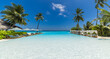 © icemanphotos - Luxury beach resort infinity pool landscape. Summer vacation destination with tall palm trees and empty sun loungers. This idyllic tropical travel scene and peaceful relaxation background picture