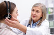 © New Africa - Hearing test. Doctor adjusting patient's audiometric headphones in clinic, selective focus