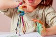 © zwiebackesser - A child holding paintbrushes with colorful hands — a symbol of early creative freedom.