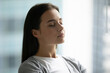 © fizkes - Inner peace. Close up shot tranquil beautiful young woman dressed in casual relax with closed eyes in light room taking deep breath of fresh air enjoy quiet meditation practice feel calm peace of mind