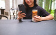 © Farknot Architect - Closeup image of a woman holding and using mobile phone while drinking coffee in cafe