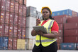 © amorn - Cargo container and Import, export , African American worker inspecting and control of cargo container. Female worker working and managing container at container yard